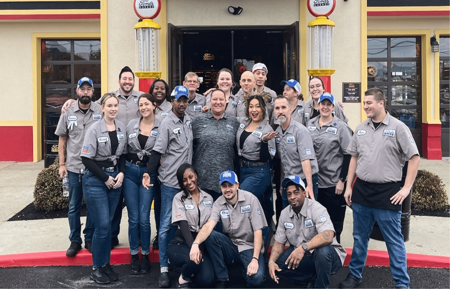 A diverse group of people stands together in front of a restaurant, smiling and enjoying each other's company.
