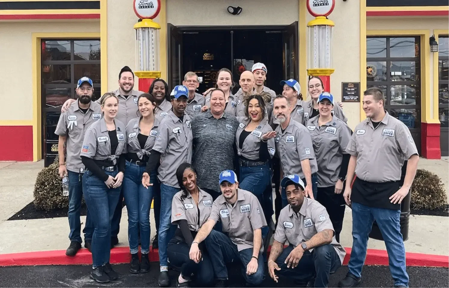 A diverse group of people stands together in front of a restaurant, smiling and enjoying each other's company.